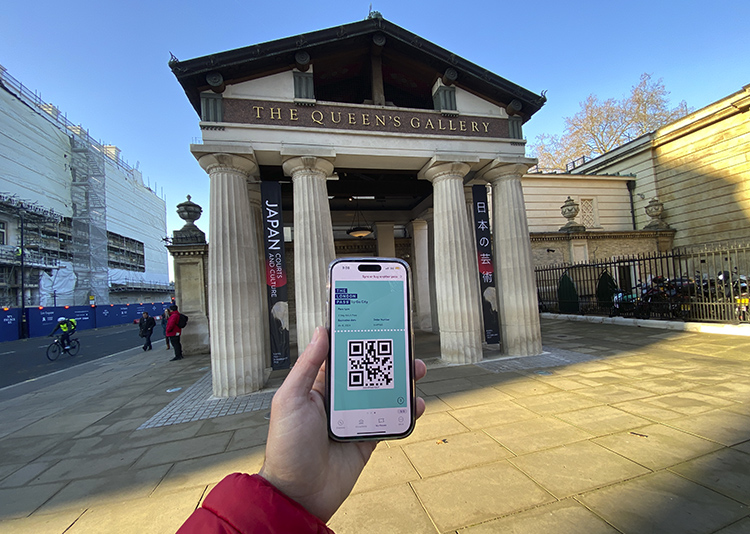Mano con un móvil con el London Pass frente a la Galería de la Reina, parte del Buckingham Palace